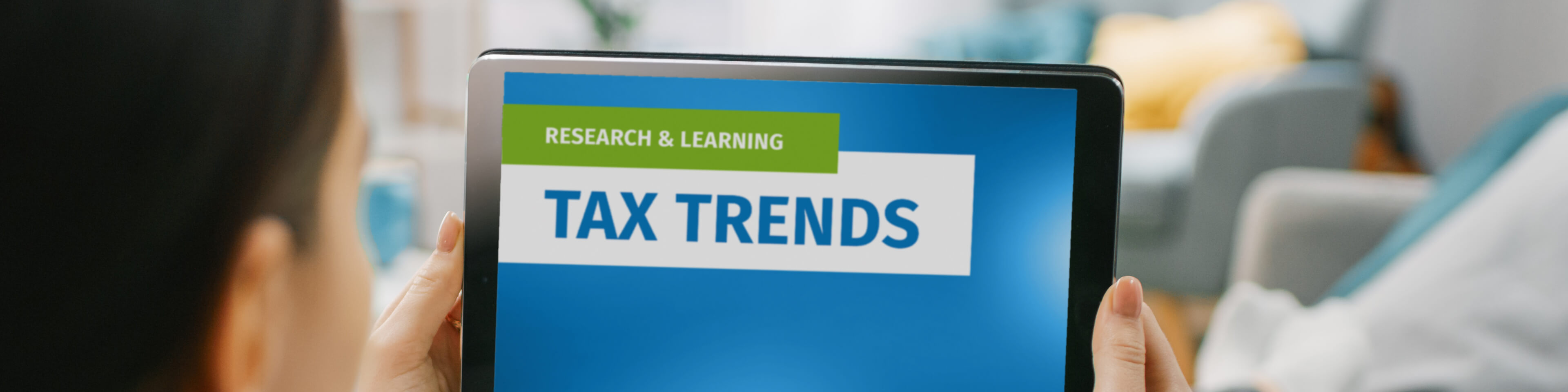 hands typing on a laptop, graphic overlay "Research and Learning Tax Trends"