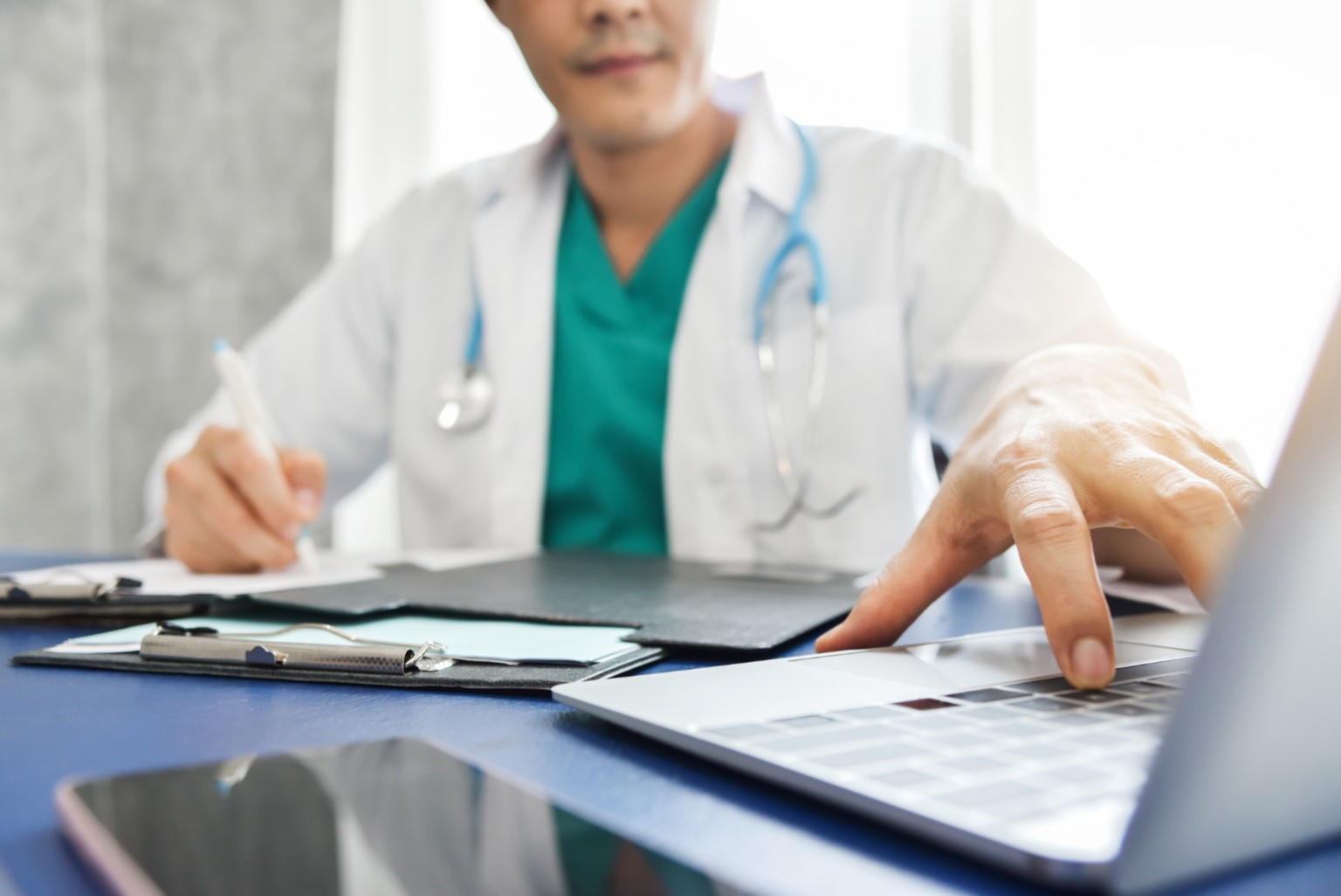 Young-Asian-male-Doctor-thinking-and-working-with-laptop-at-a-hospital-Medical-and-health-care-conce