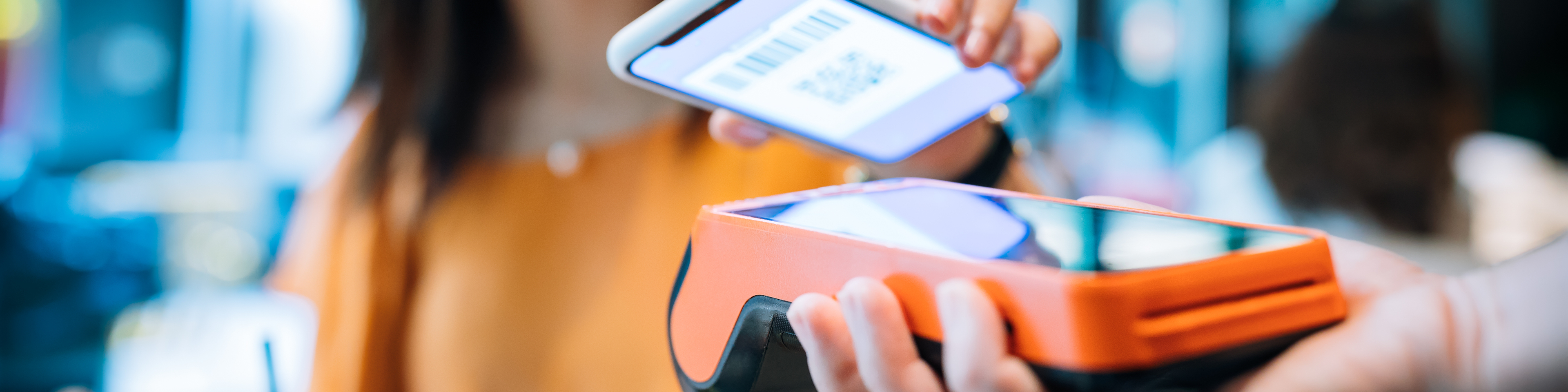 Young woman paying with smartphone in a cafe