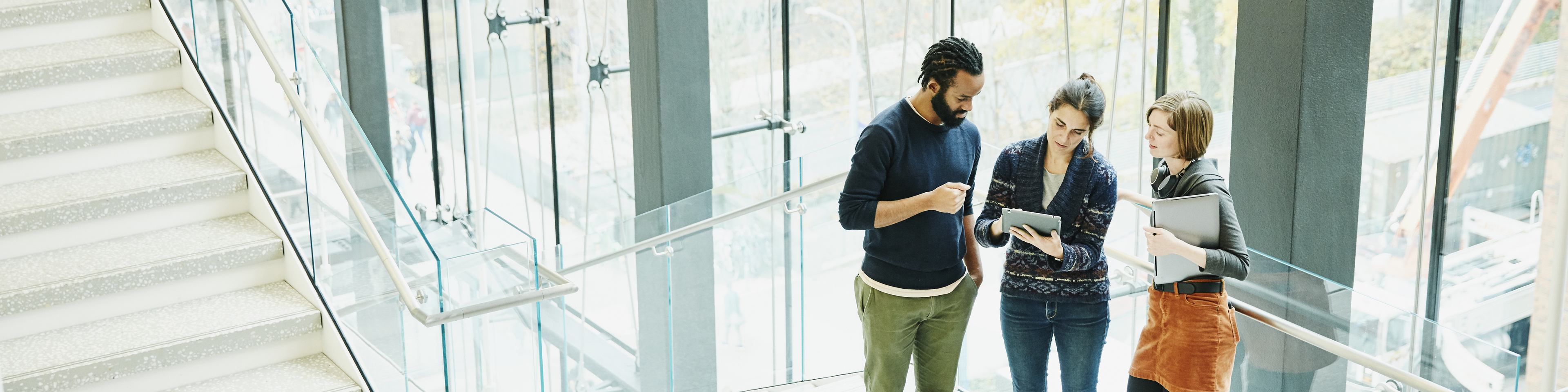 Coworkers discussing project on digital tablet on stairs of office building