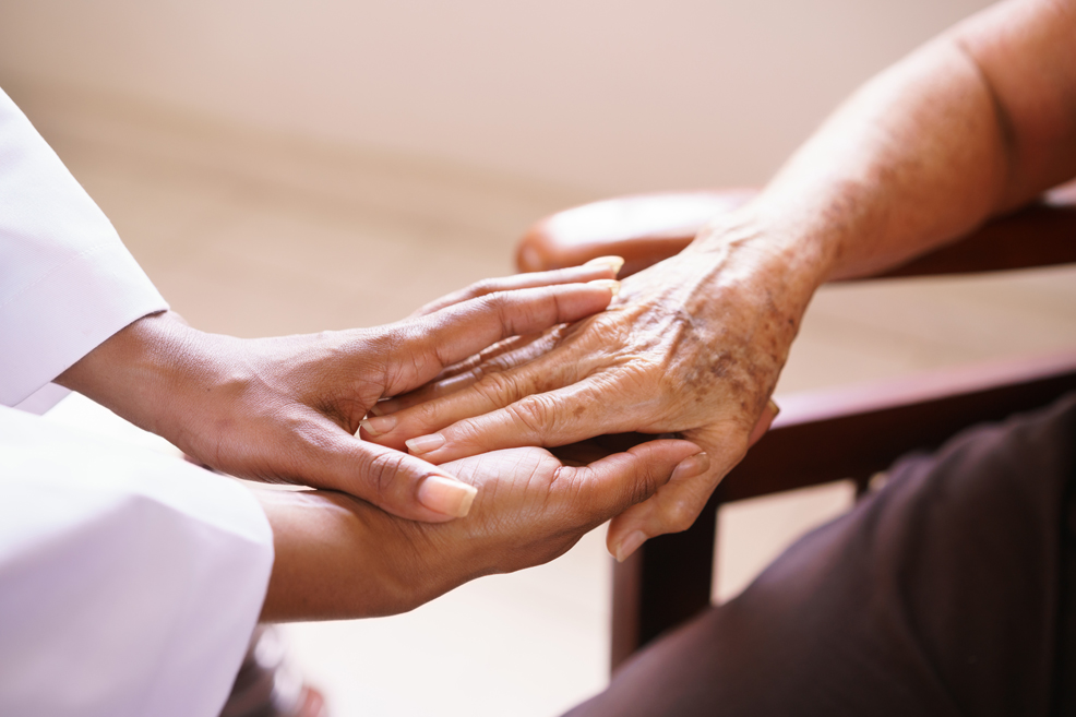 Doctor holding an older woman's hands within hers
