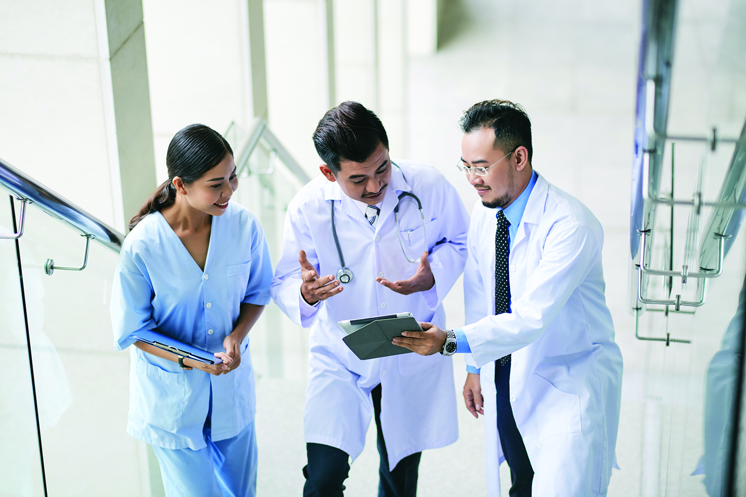 Asian doctors walking up the stairs and discussing information on tablet computer