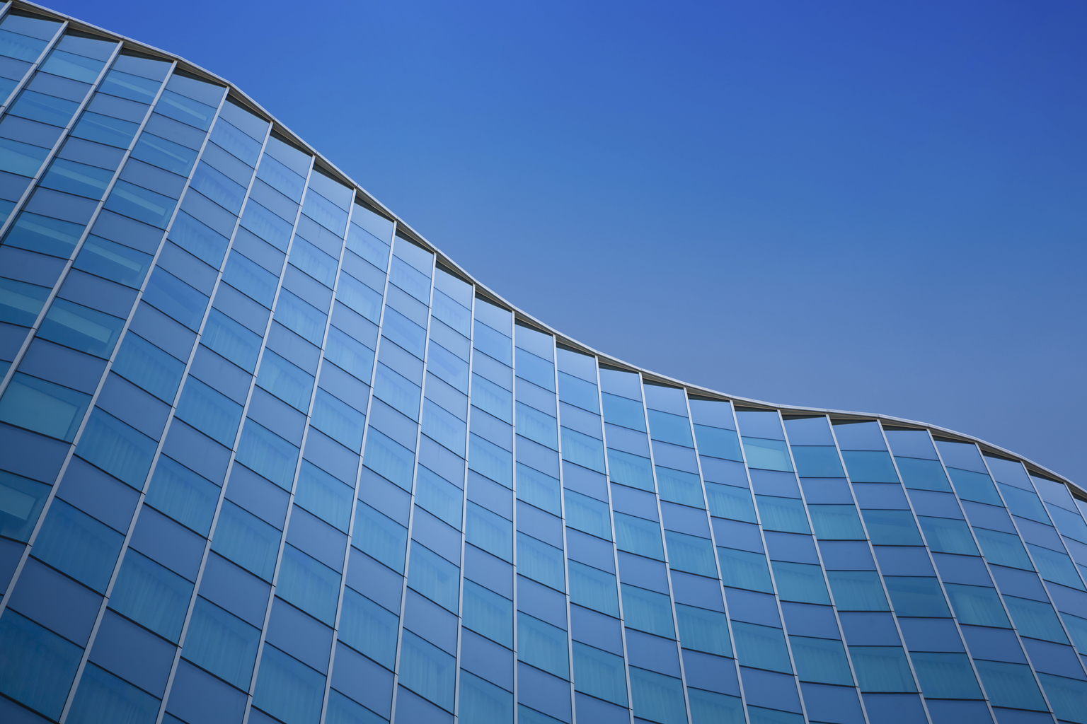 Close up of a modern architecture with blue sky background - glass building exterior