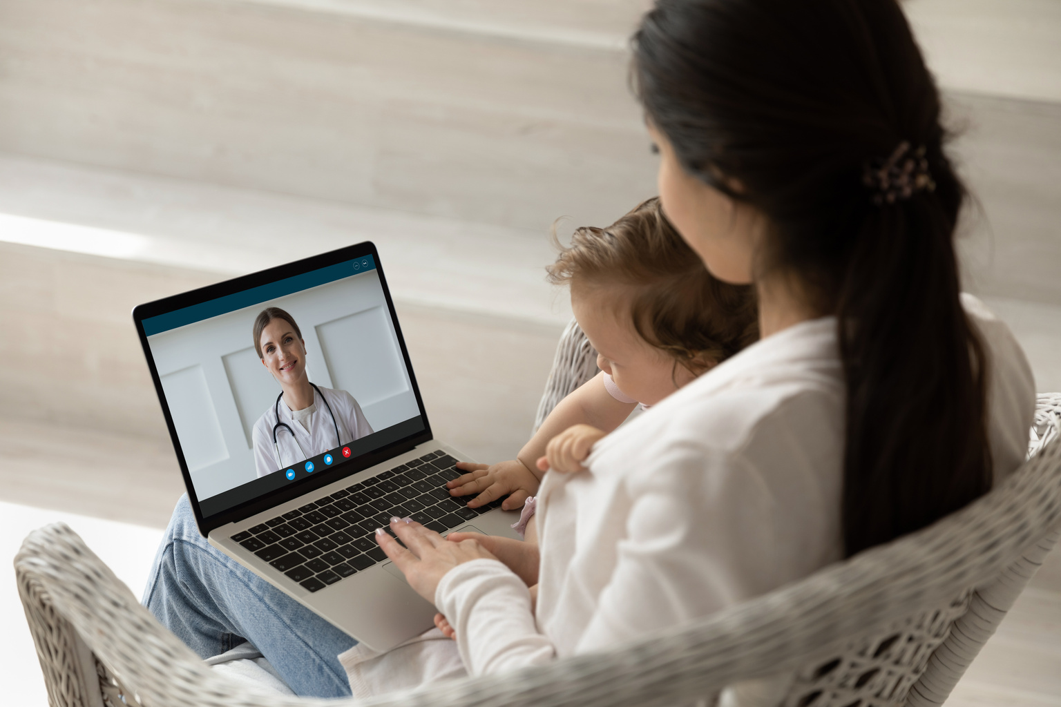 Mother and child sitting together on a telehealth call with healthcare professional