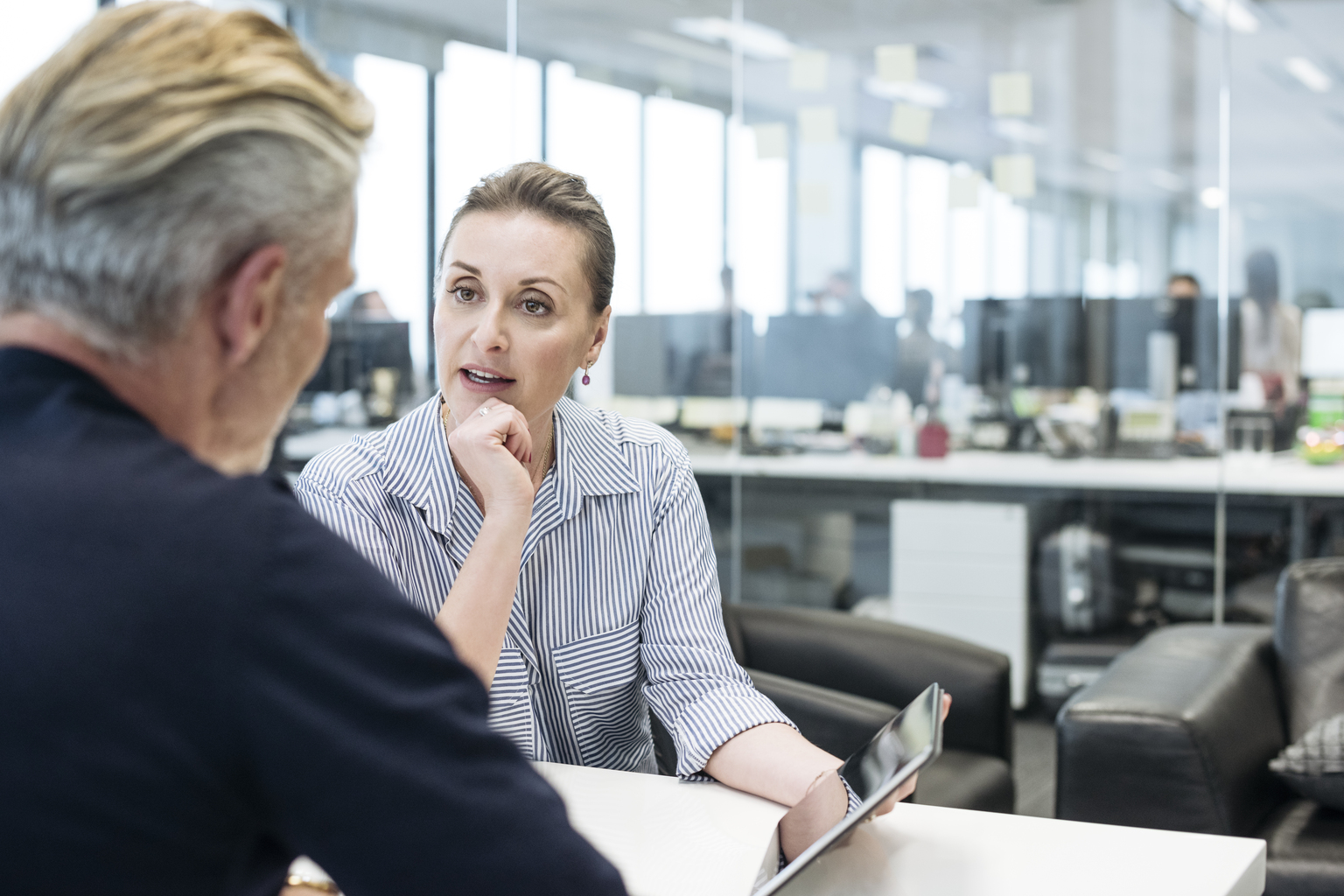 Businesswoman pointing to tablet and explaining to male colleague