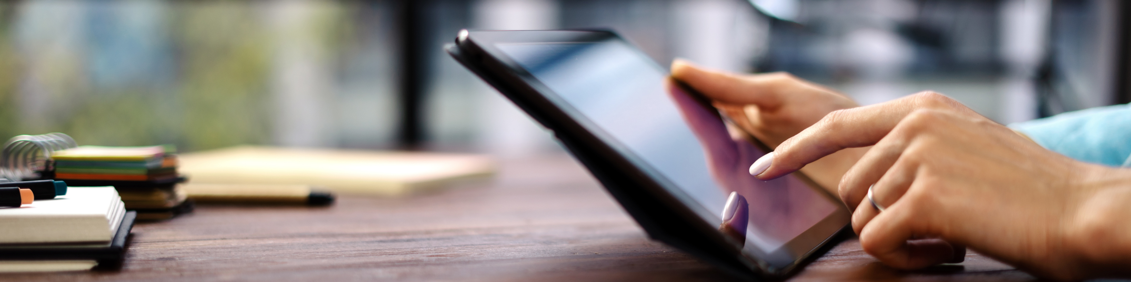 Woman pointing on digital tablet screen sitting at desk