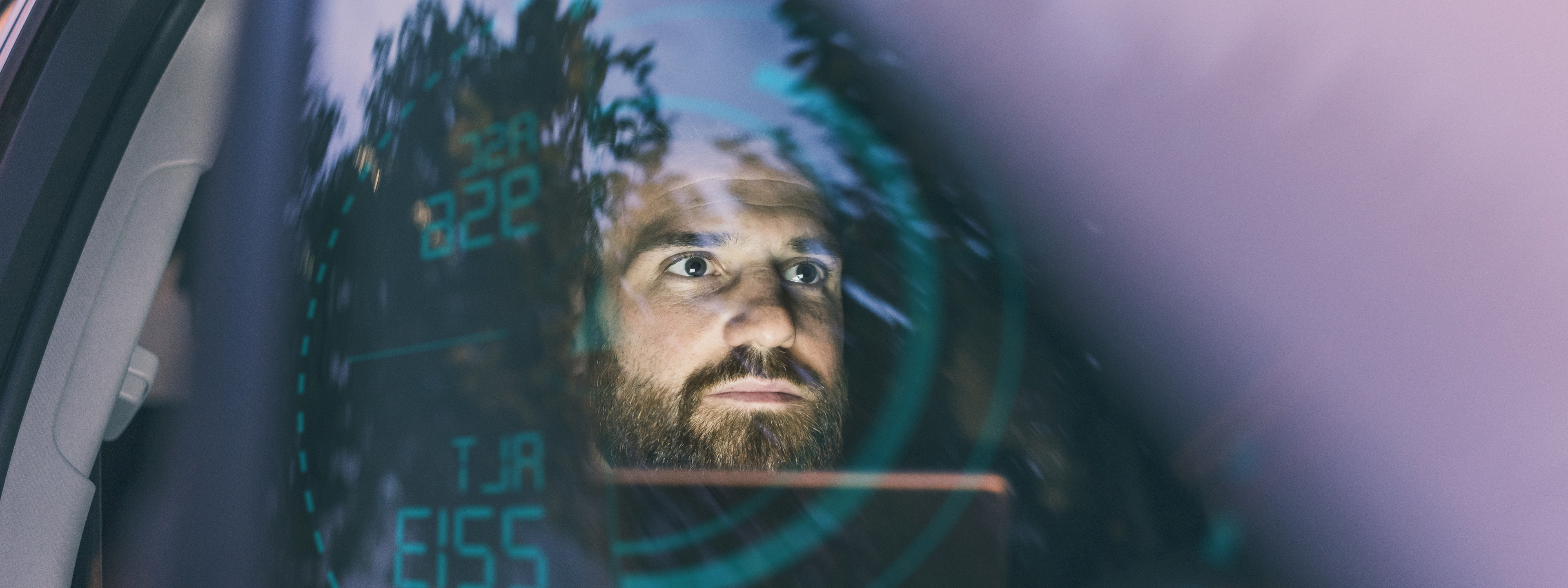 Focused man in car at night surrounded by dashboard projection