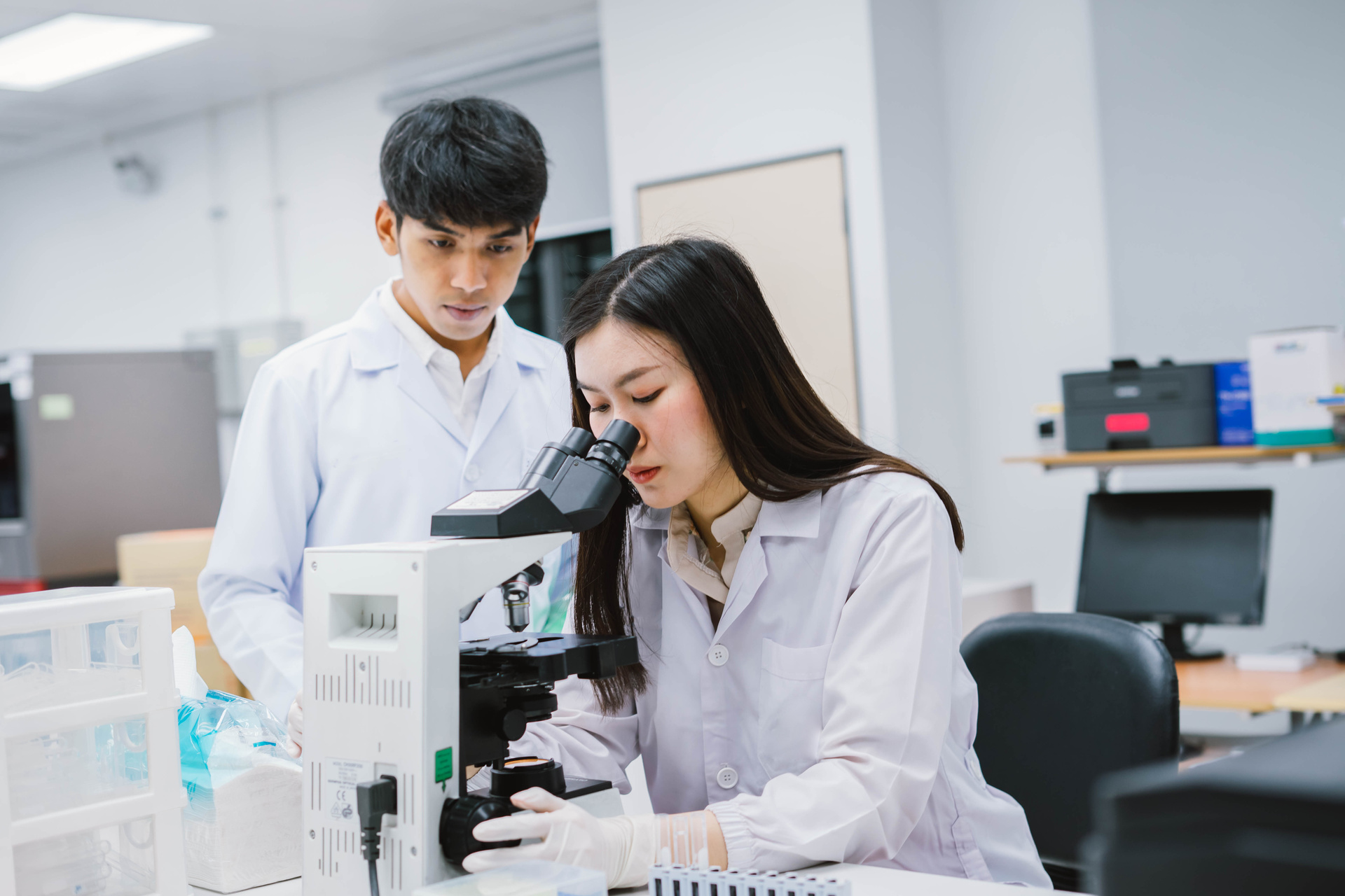 Two researchers in a labratory using microscope