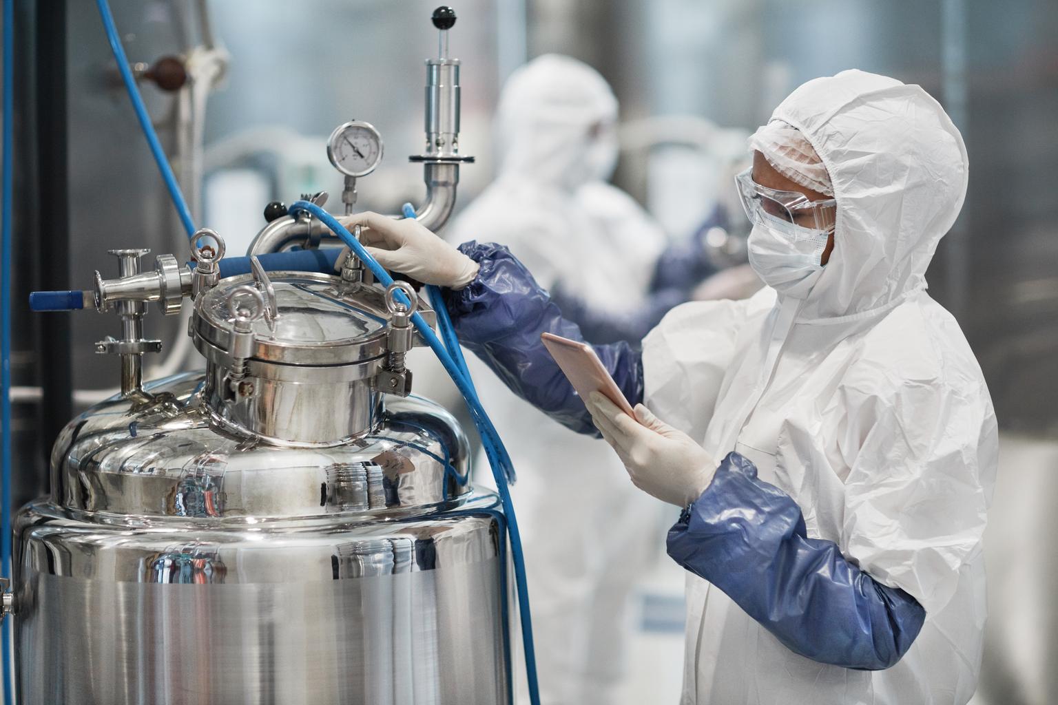 Portrait of female worker wearing protective suit while operating equipment at modern chemical plant, copy space