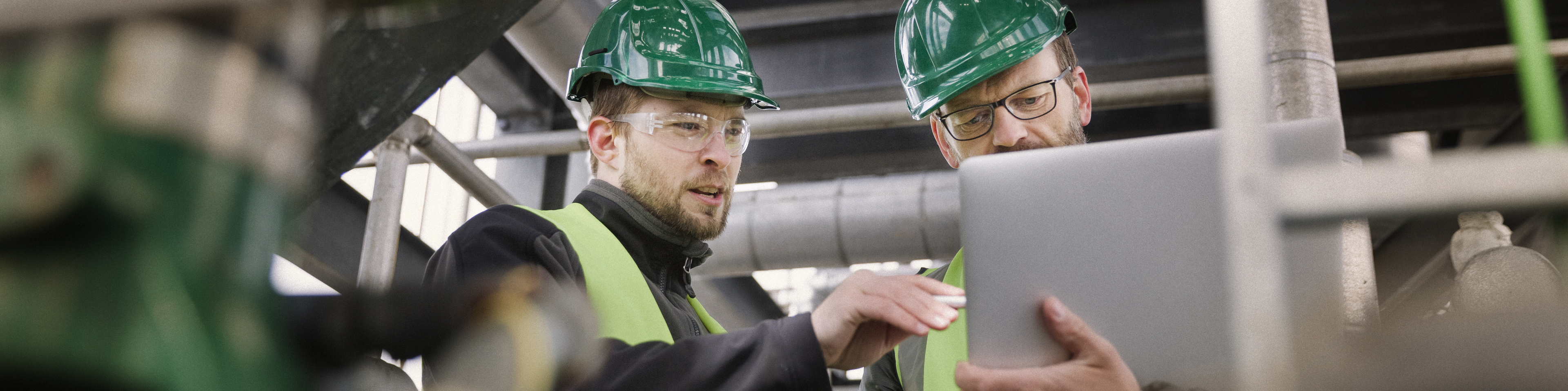 Manual workers discussing while using laptop at factory