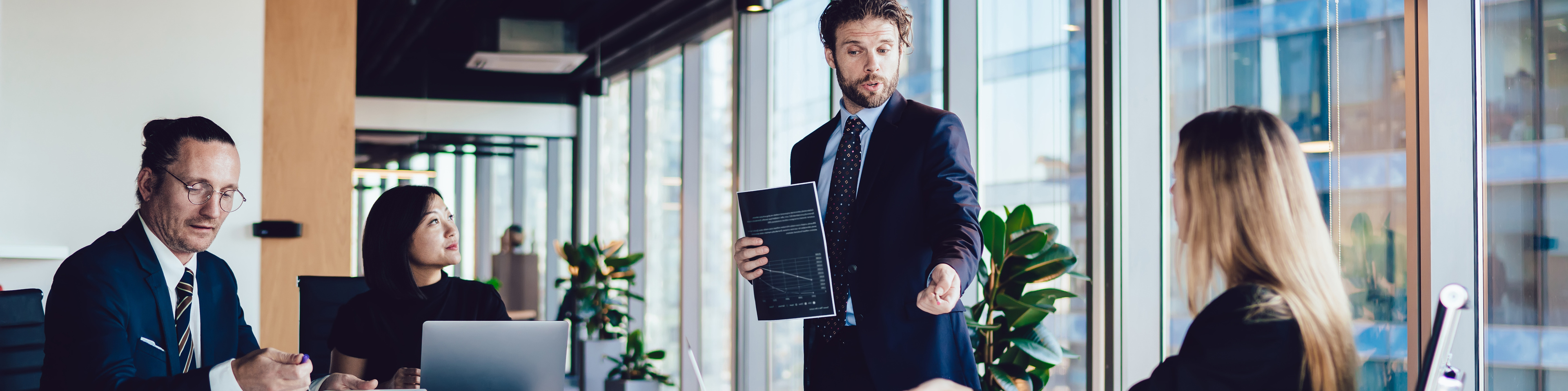 Male CEO with paper document talking to employees