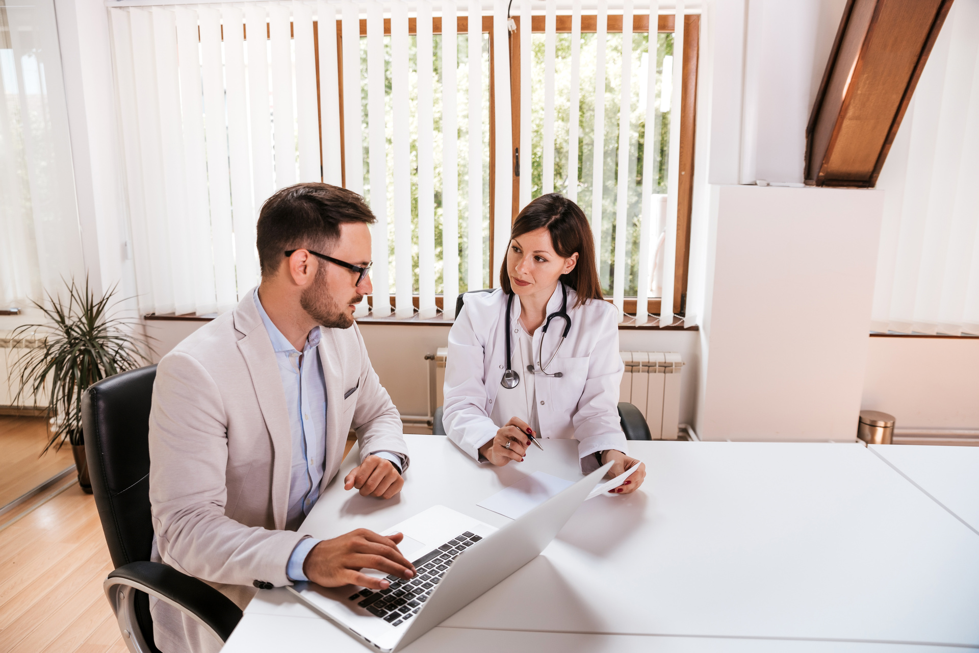 Hospital administrator and doctor discussing with laptop