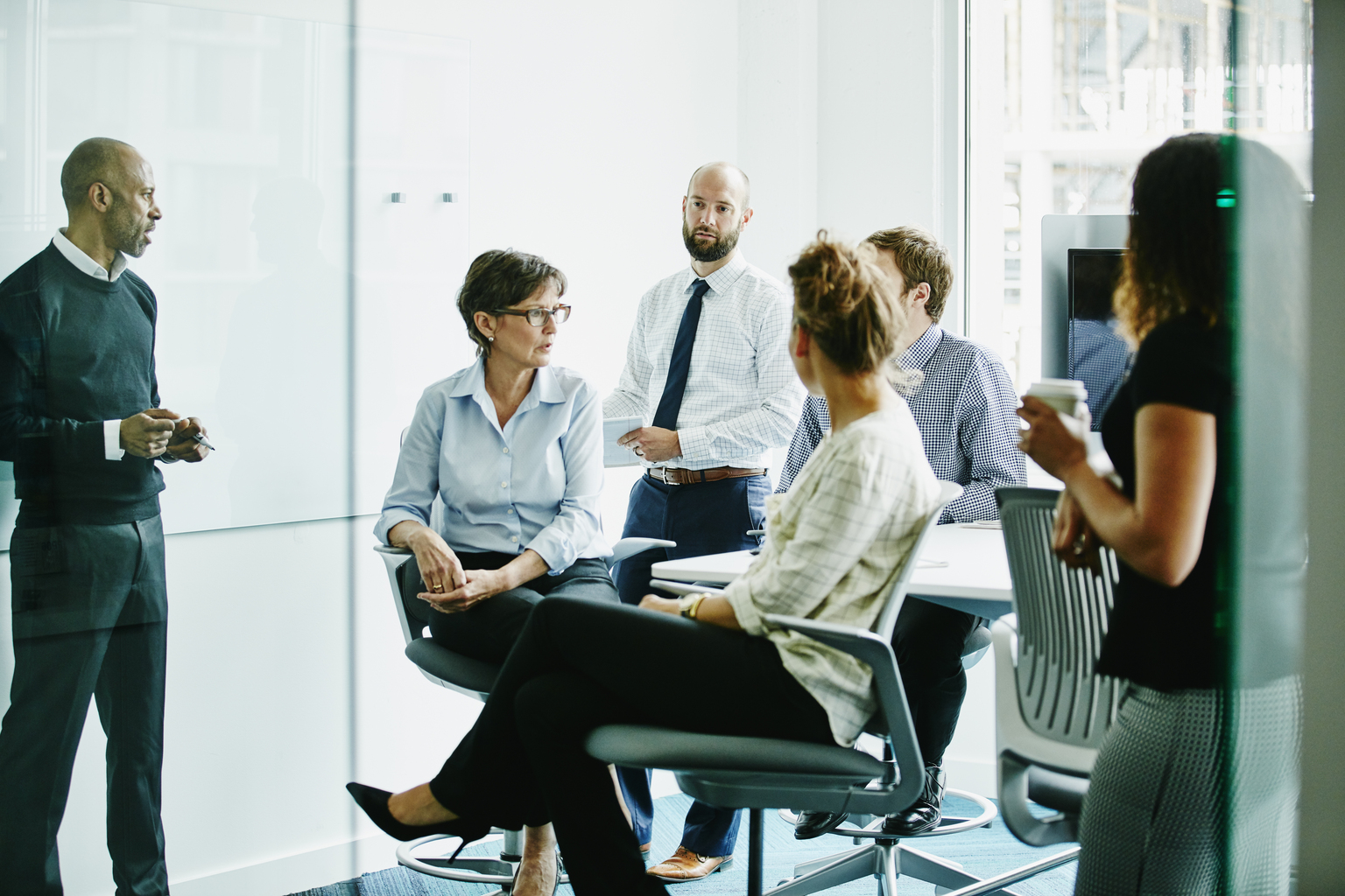 Mature businesswoman leading discussion with colleagues during team meeting in conference room