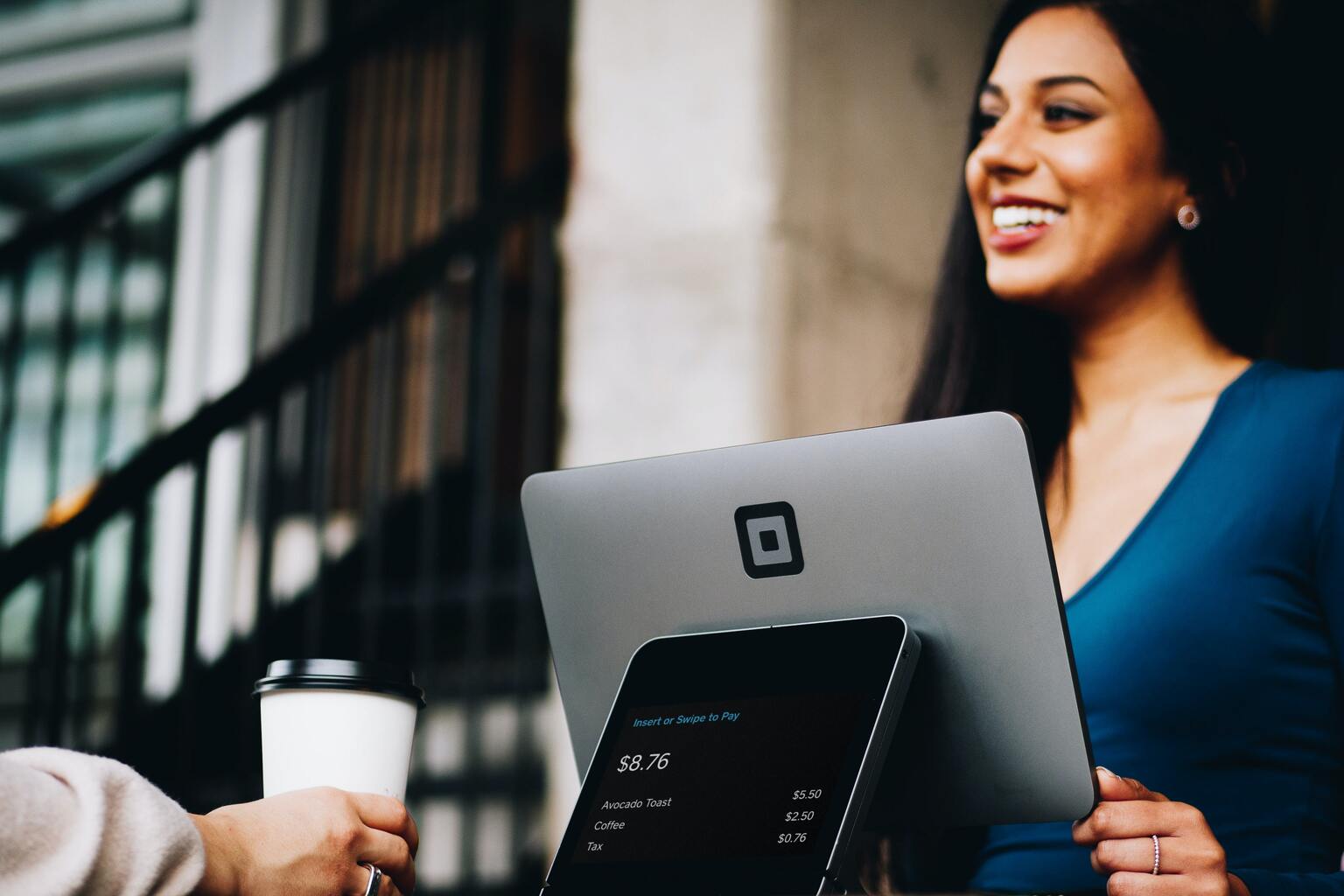 Female cashier standing at register computer and smiling at customer