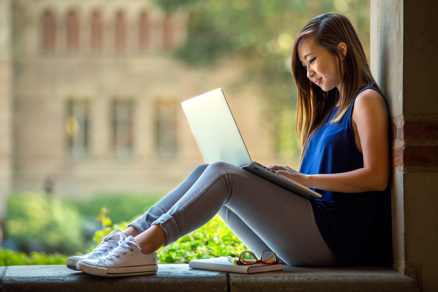Woman sitting in courtyard on laptop