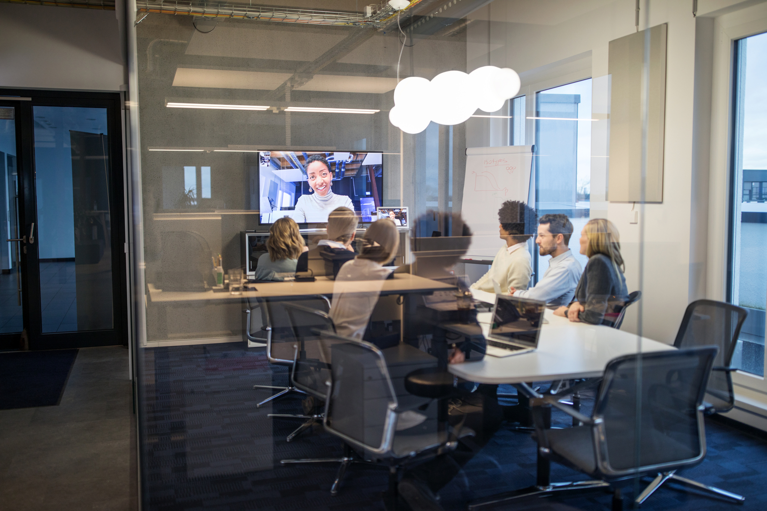 Group of business people having a video conference meeting inside a board room. Businessmen and business women sitting around a conference table talking and networking