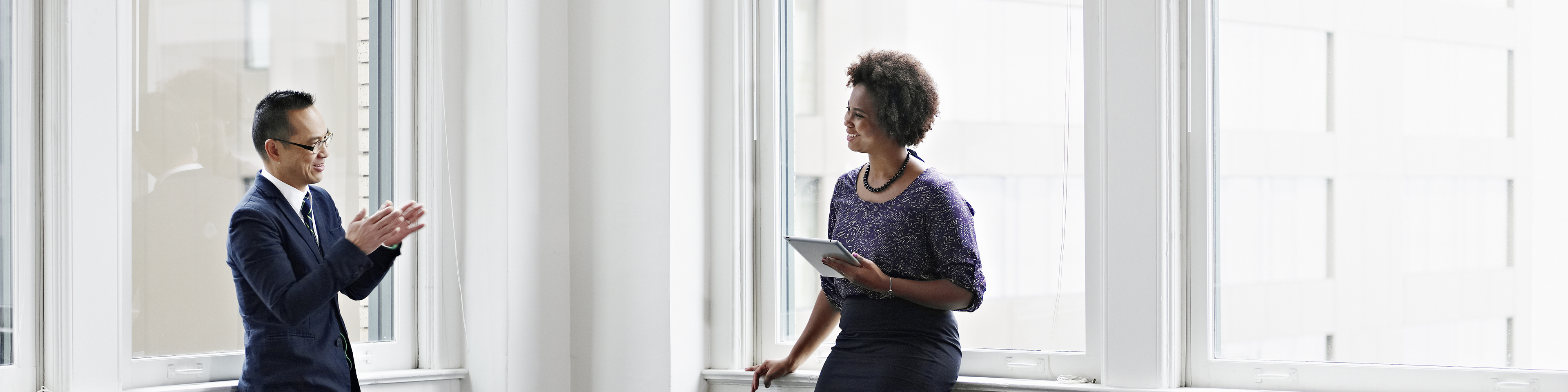 Smiling businesswoman holding digital tablet in discussing project with businessman in office