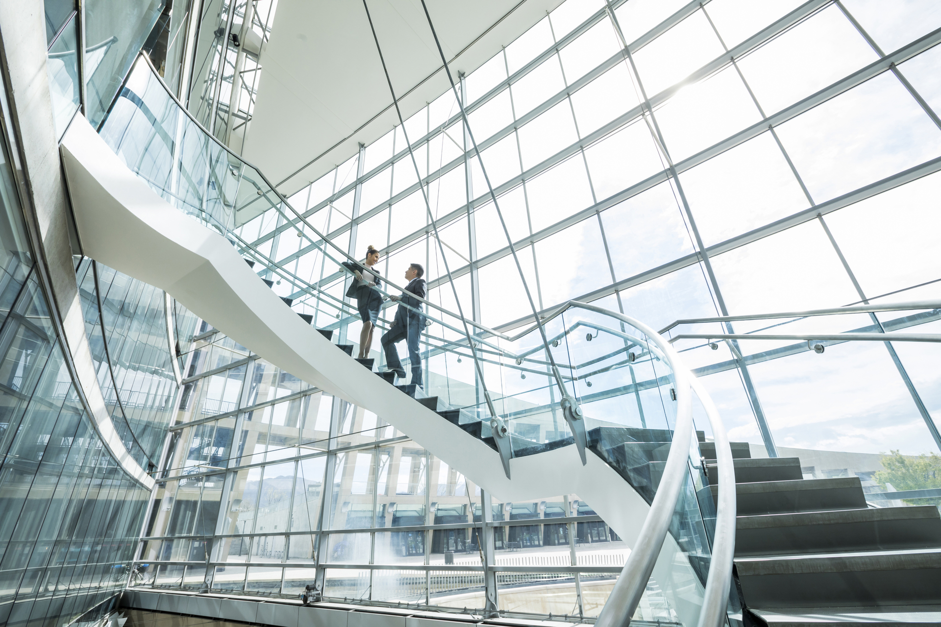 Distant Mixed Race business people standing on staircase and talking