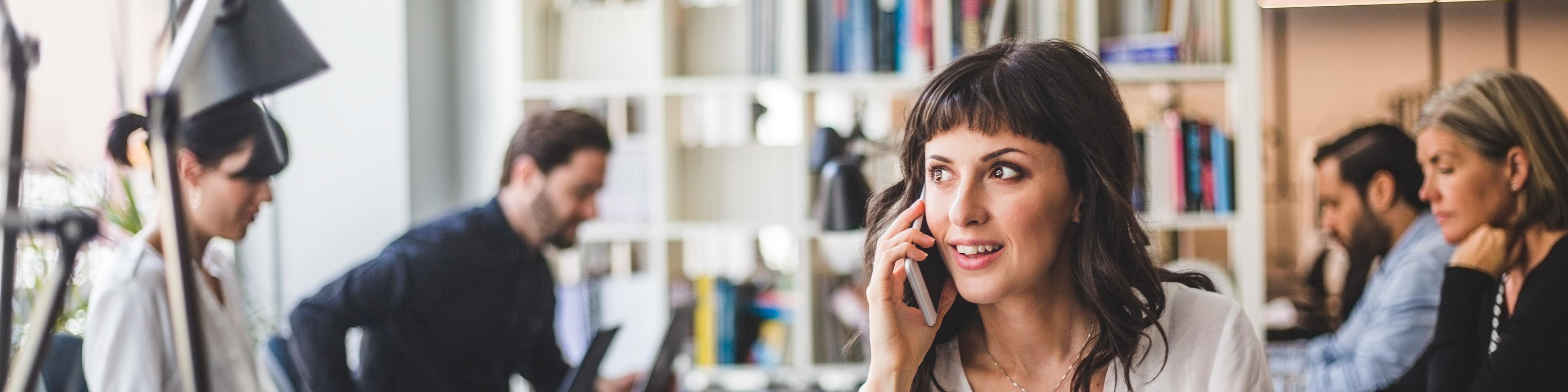 Businesswoman looking away while talking on mobile phone at desk in creative office
