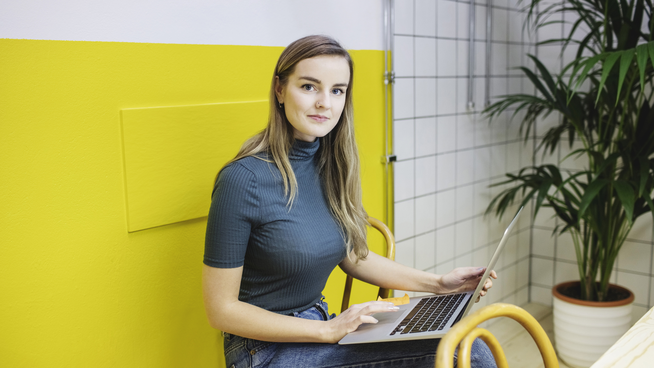 Portrait of confident young woman using laptop in office