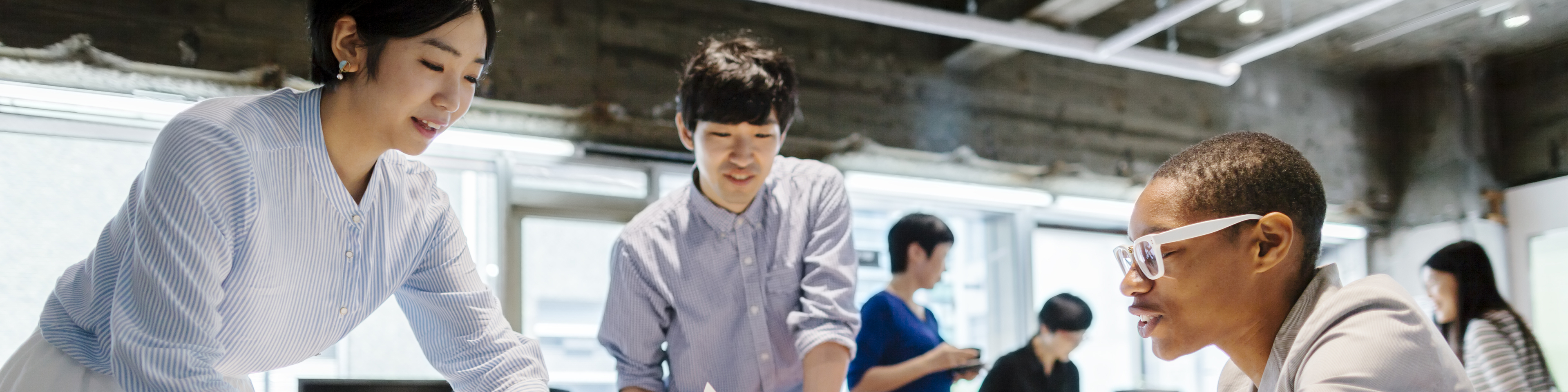 A group of multi-ethnic young business people are talking to each other in a modern working space in Tokyo.