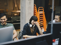 Happy female computer programmer sitting with male colleagues in office