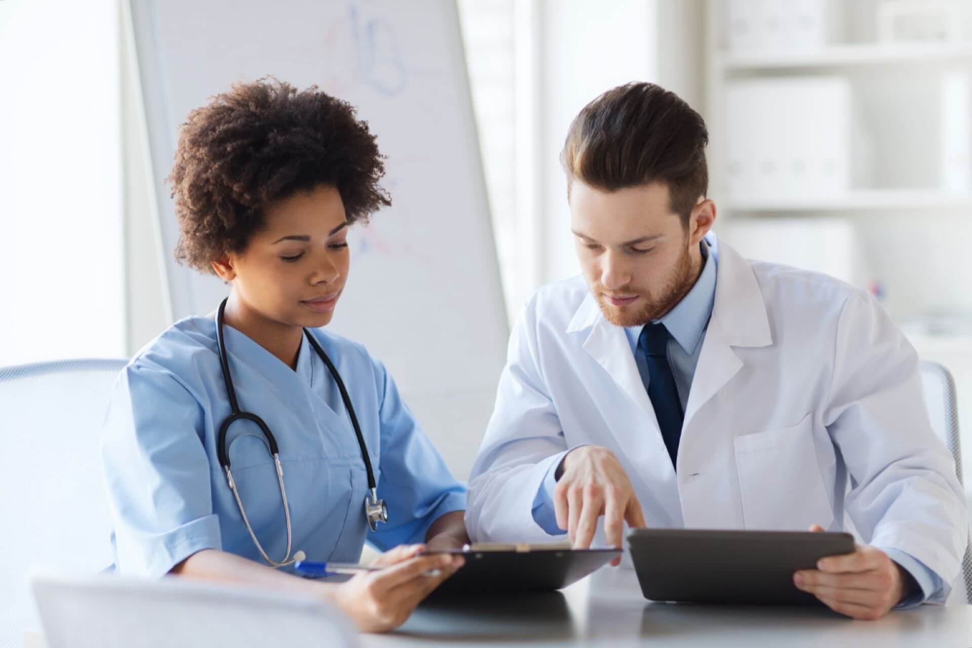 hero -two doctors with tablet pc computer meeting and talking at medical officePNG