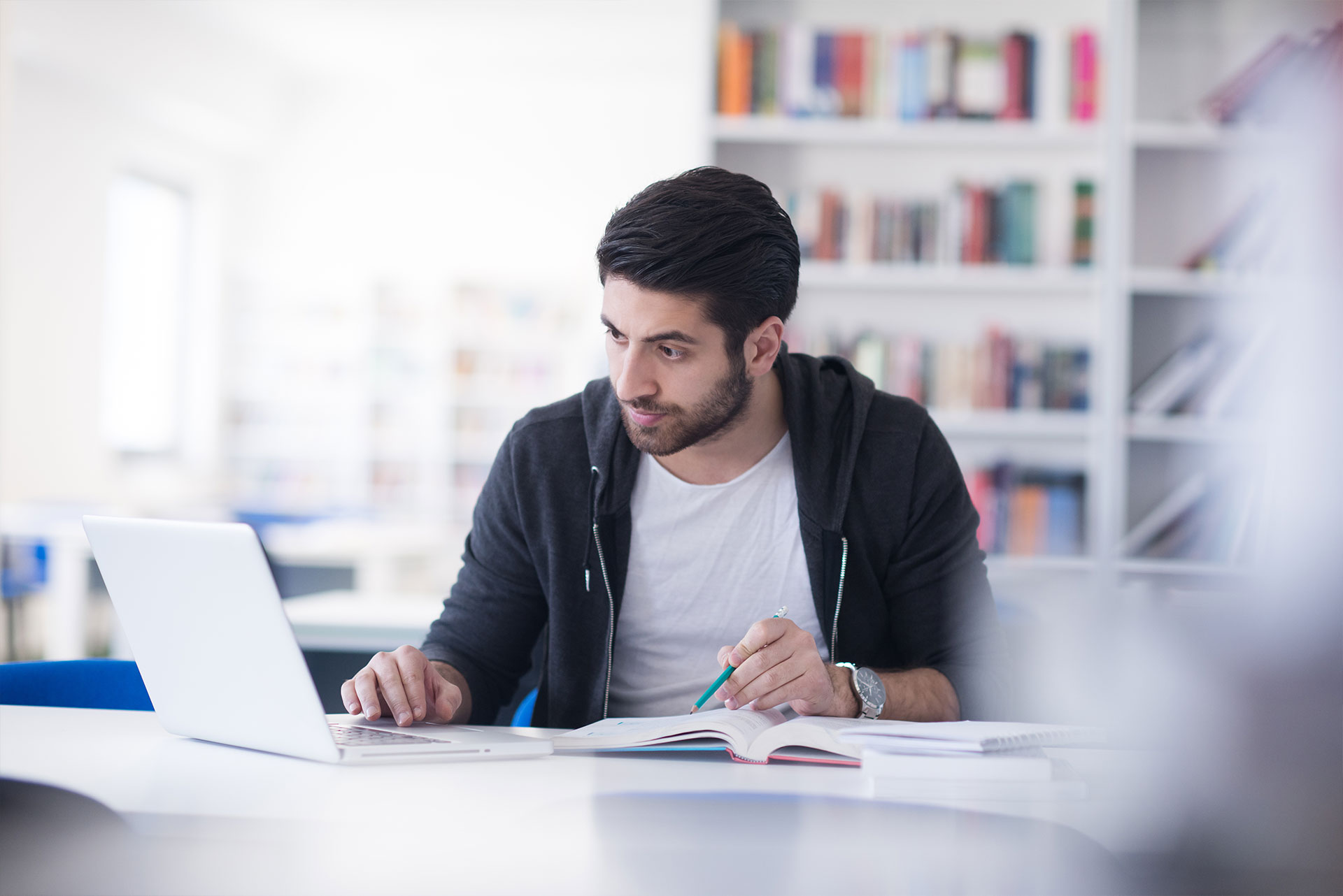 Male student studying at a desk with his laptop