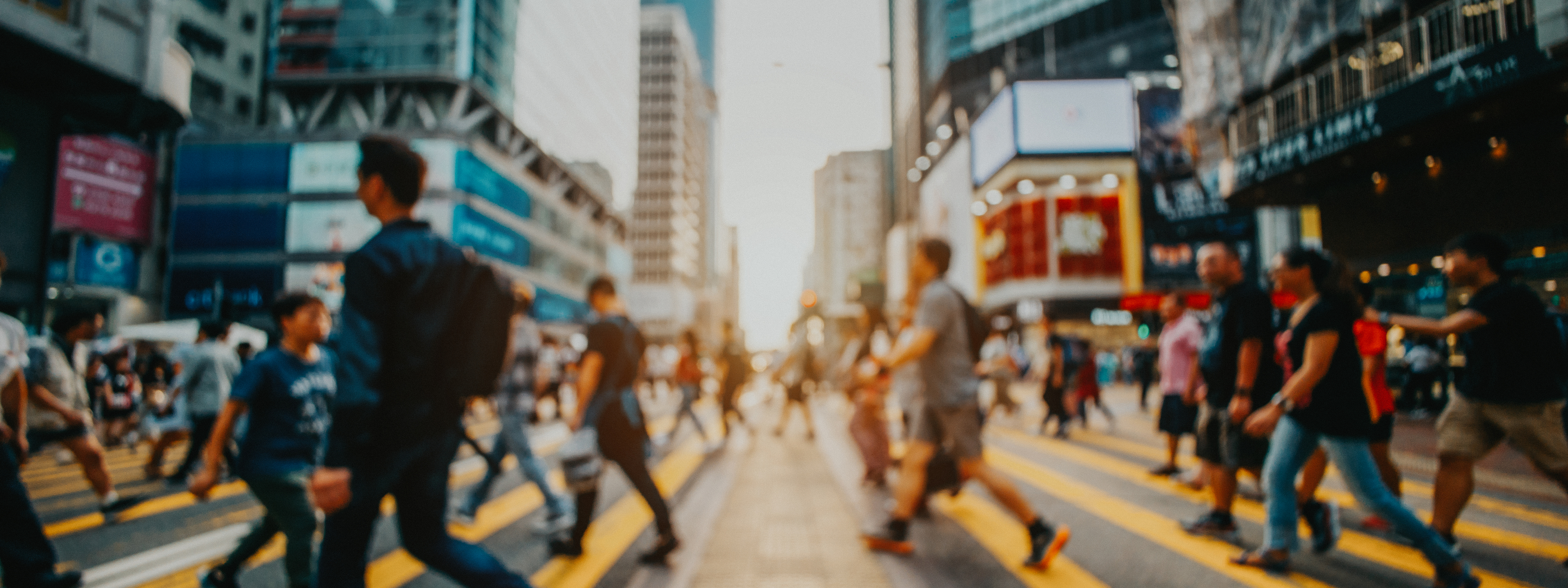 Defocused image of busy commuters crossing the street in downtown district against contemporary corporate skyscrapers