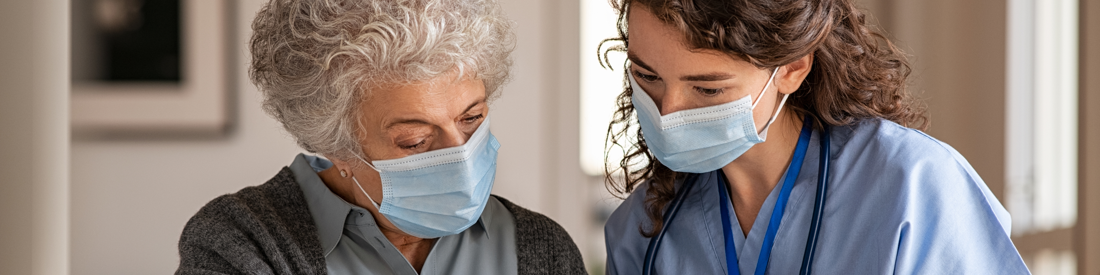 Patient wearing mask watching education video on tablet with nurse