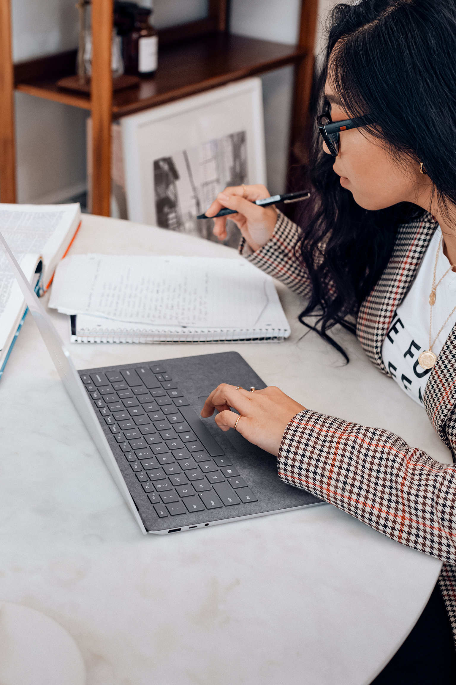 Woman working at laptop, writing notes