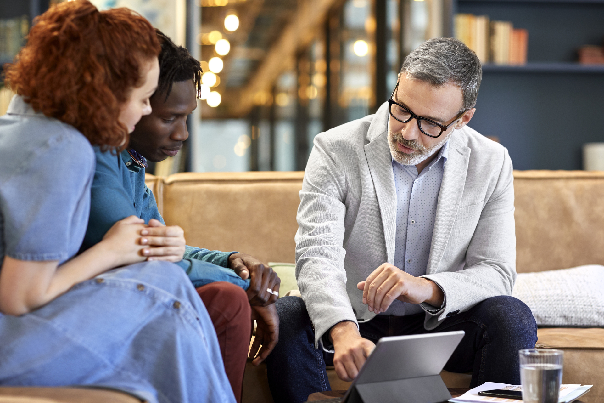 Mature financial advisor planning with young multi-ethnic couple at office