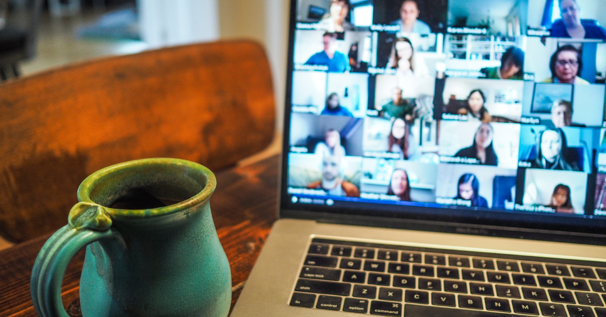 Zoom call on a laptop with coffee mug next to it on table