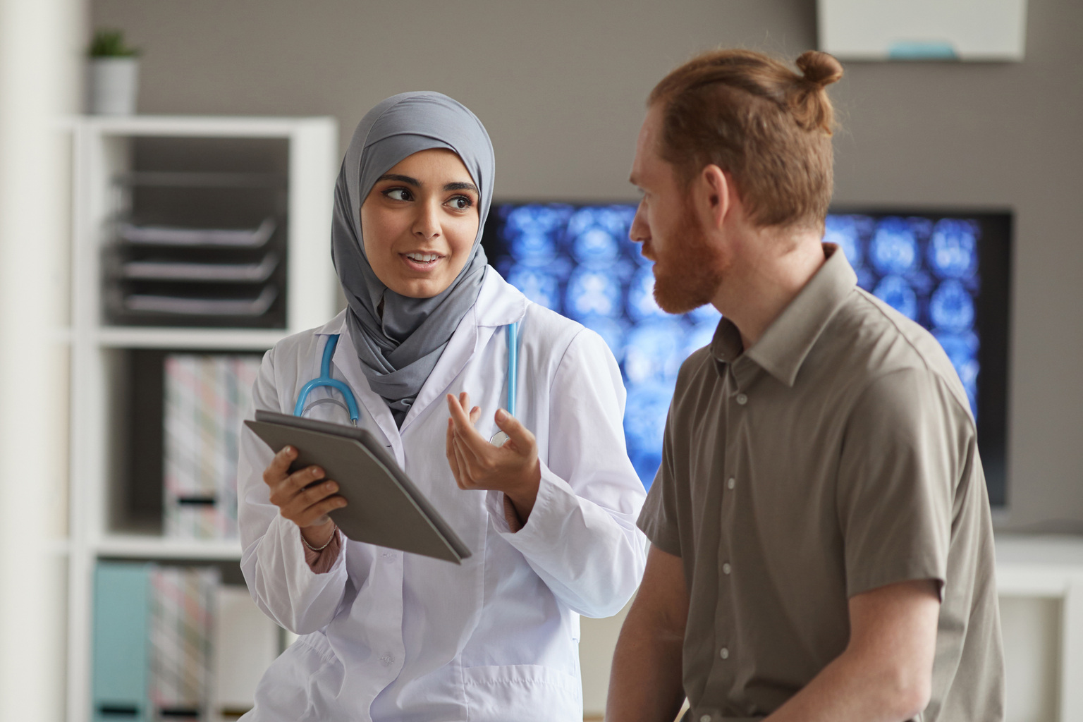 Male patient listening to his doctor while she tells about the disease using digital tablet