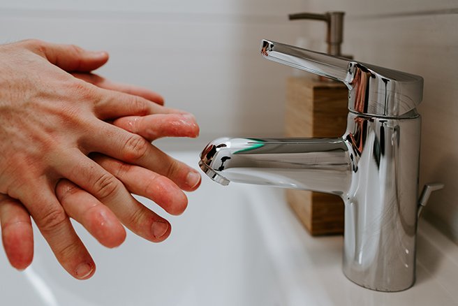 Close up on pair of hands being washed in sink