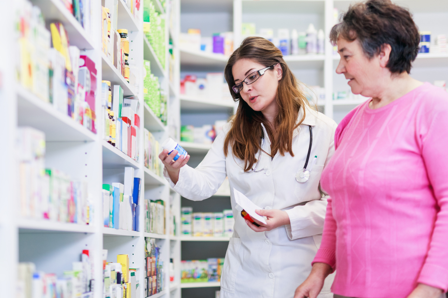Young female pharmacists advising older patient