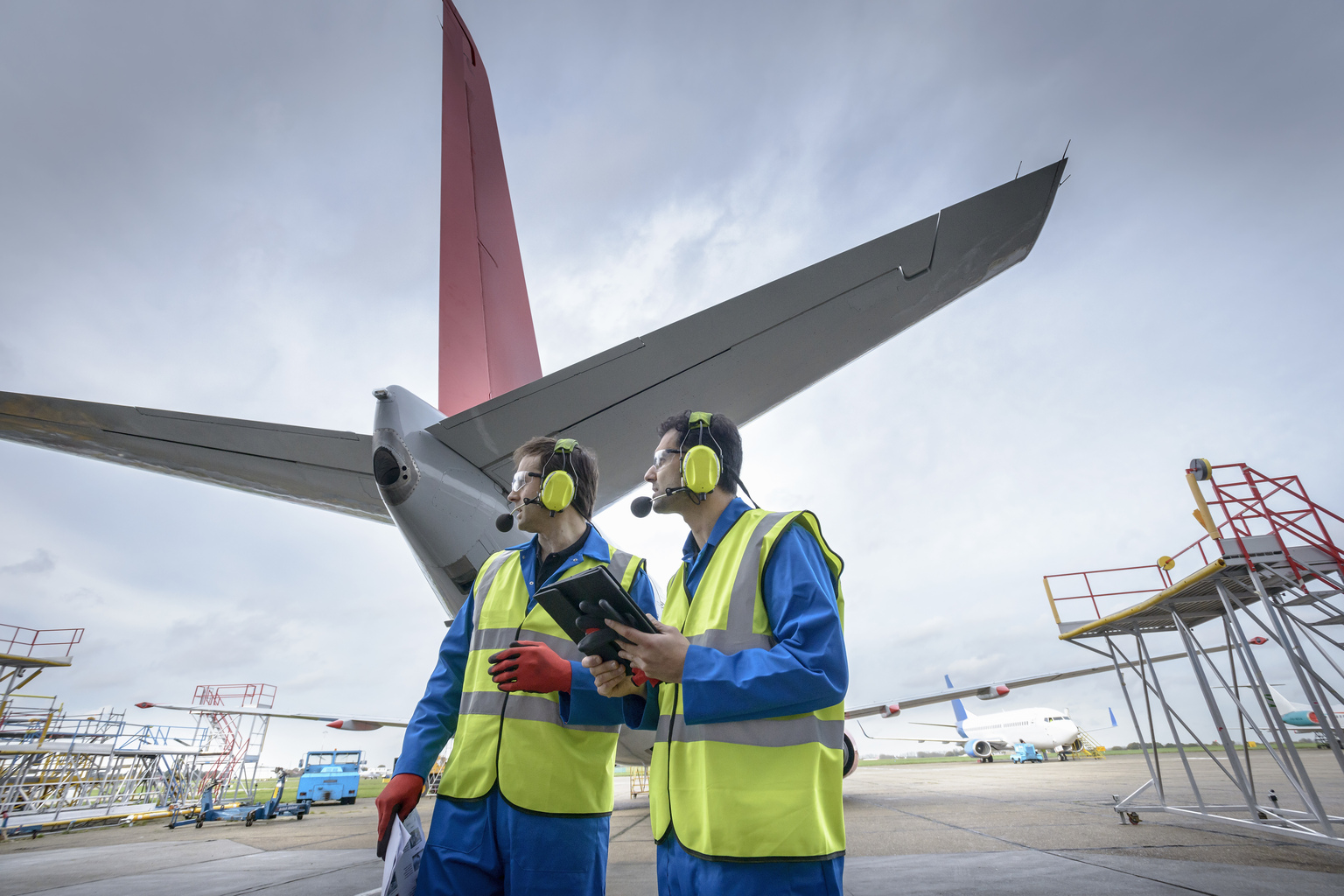 Airside engineers inspecting jet aircraft on runway