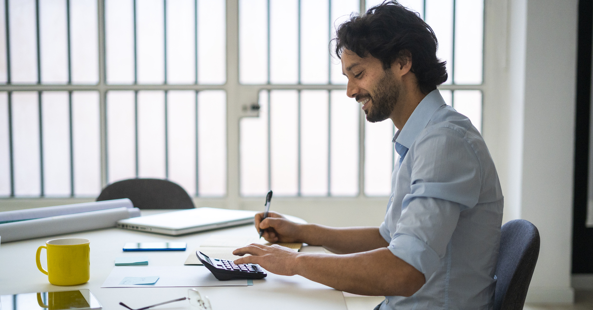 Smiling young businessman working while sitting by desk in office