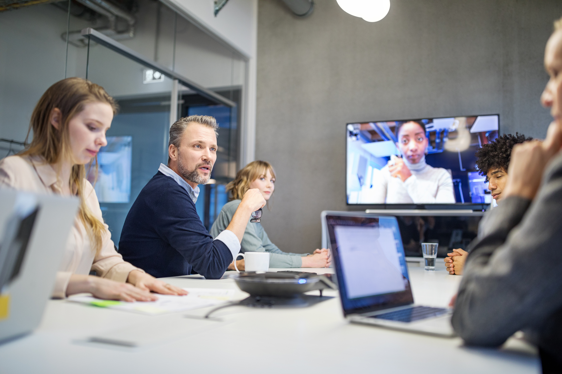 Business people in board room having video conference meeting. Group of men and women having meeting at office