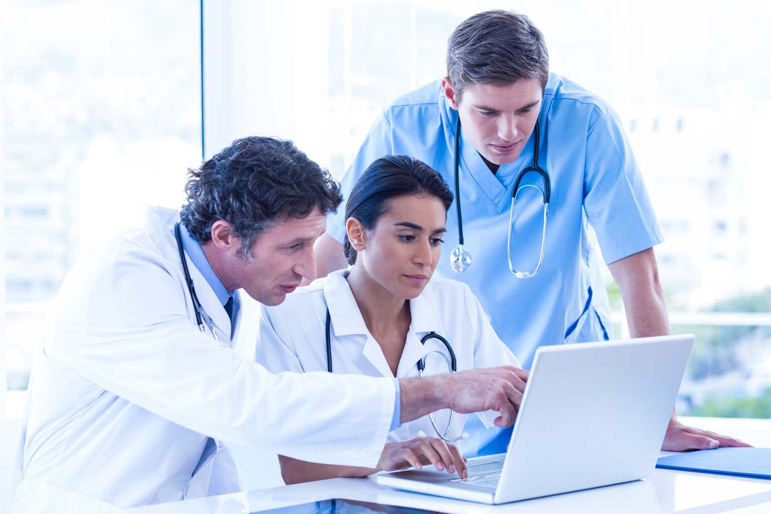 three doctors discussing information displayed on a laptop