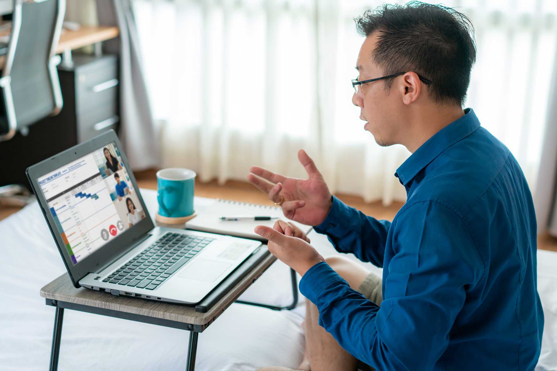 Man videoconferencing on hotel bed