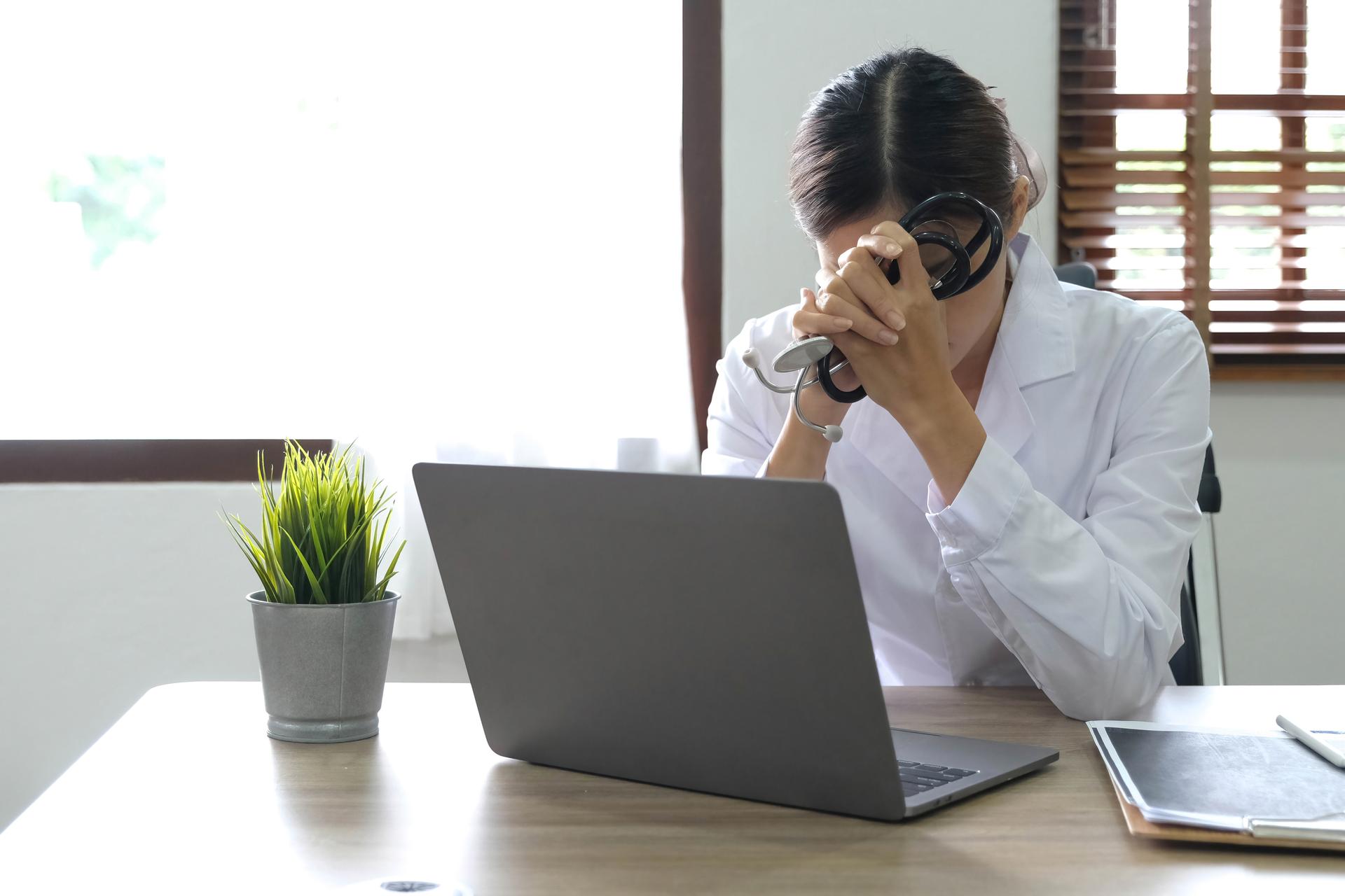 Health care professional sitting at desk, slumped in frustration