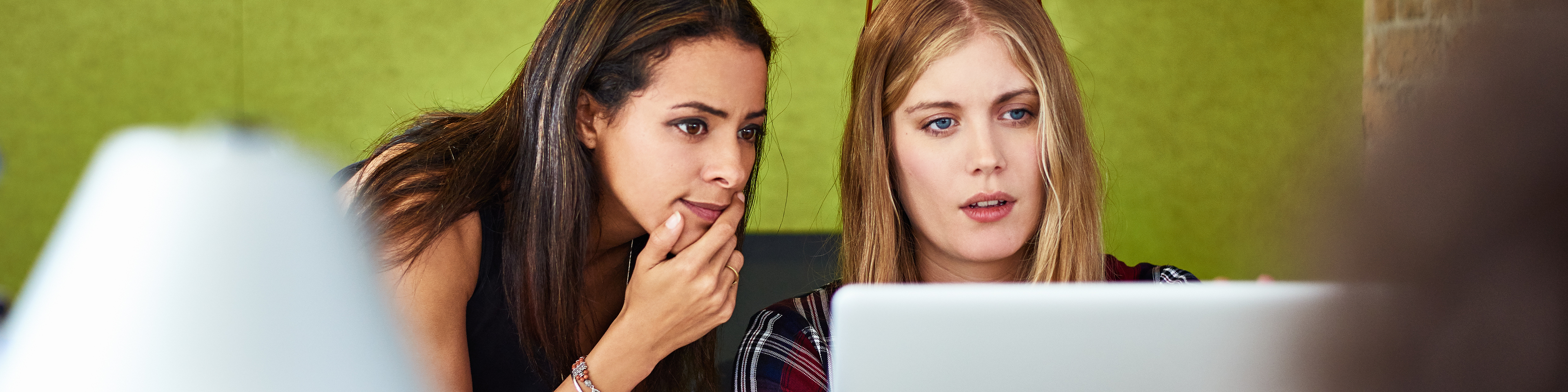 Female colleagues discussing over laptop in the office.