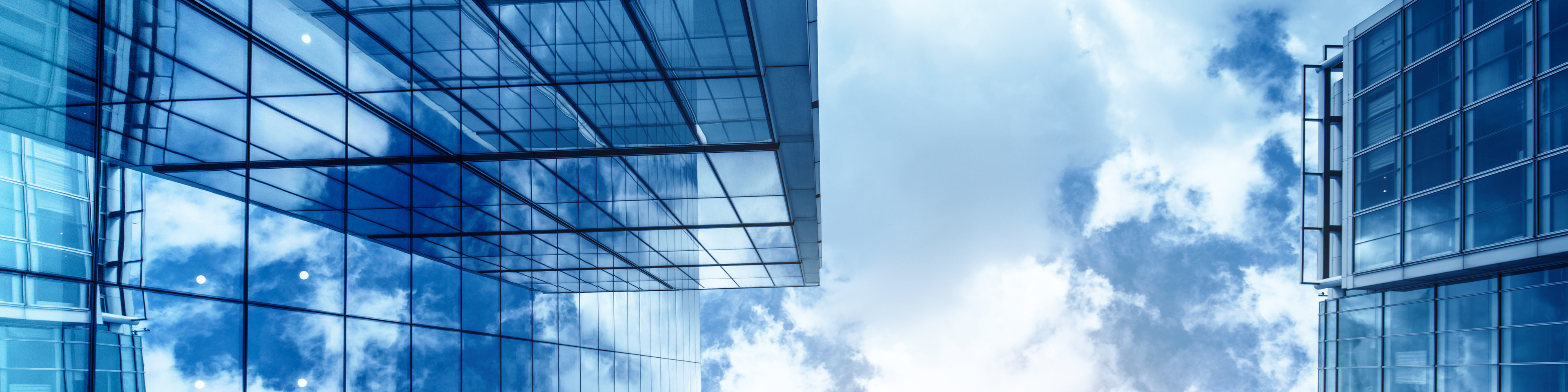 view of a contemporary glass skyscraper reflecting the blue sky