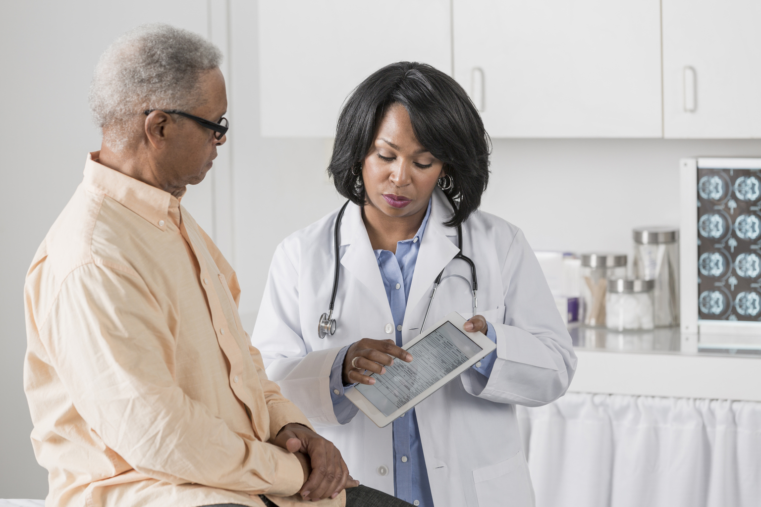 African female doctor showing African patient information on tablet.