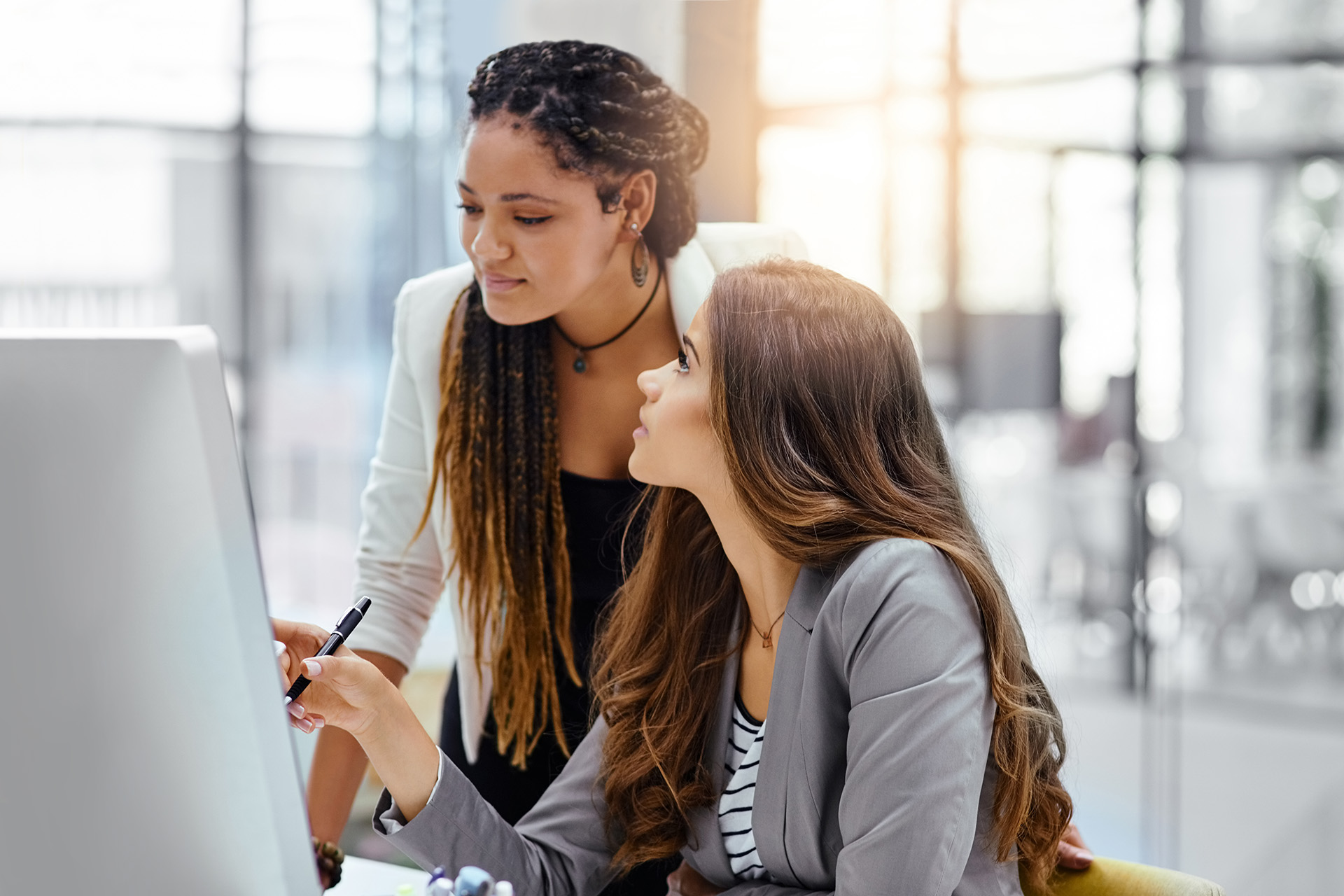 Two women having a discussion while looking at computer