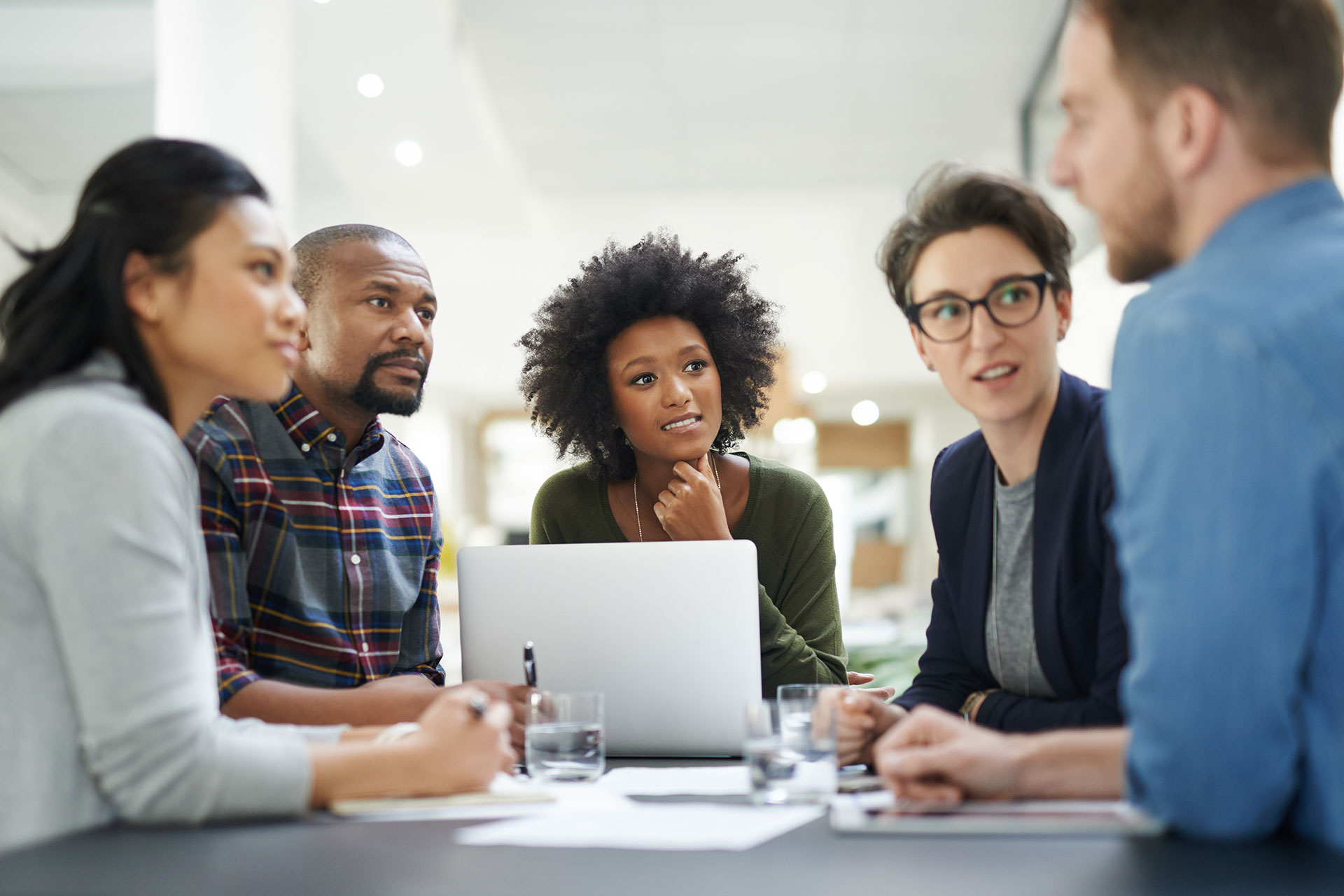 Young professionals meeting around a laptop running TeamMate.