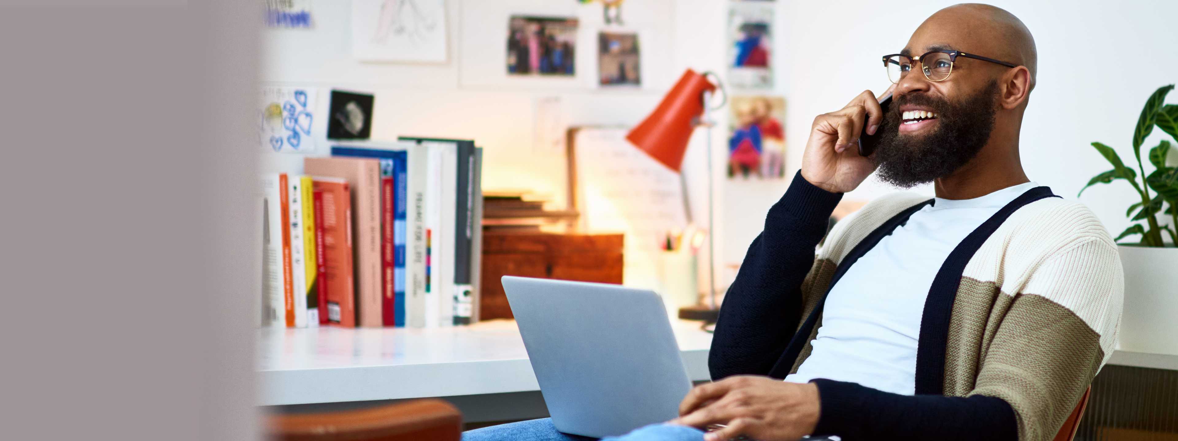 Man working on laptop from home while on phone