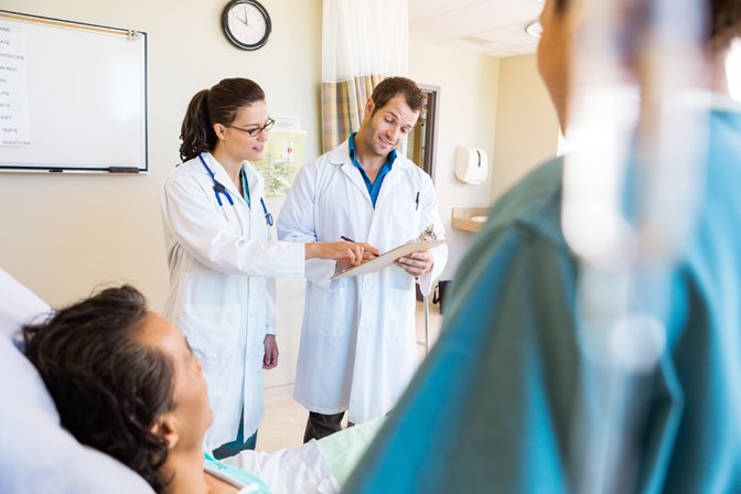 Doctors discussing notes with patient and nurse in foreground