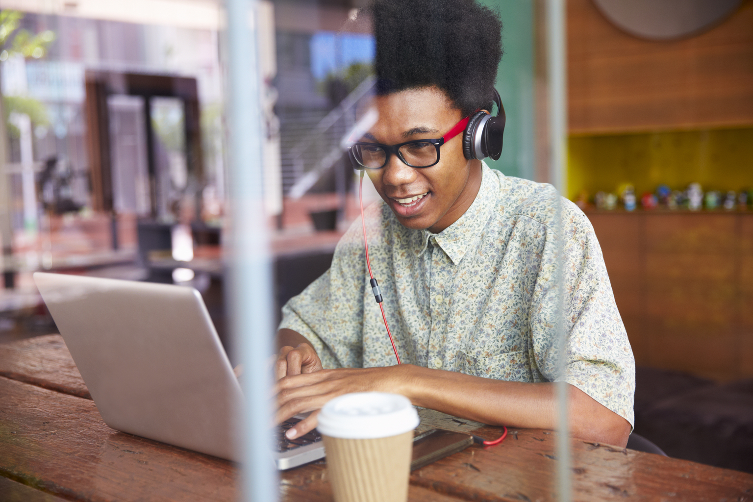 Laughing young man wearing headphones using laptop